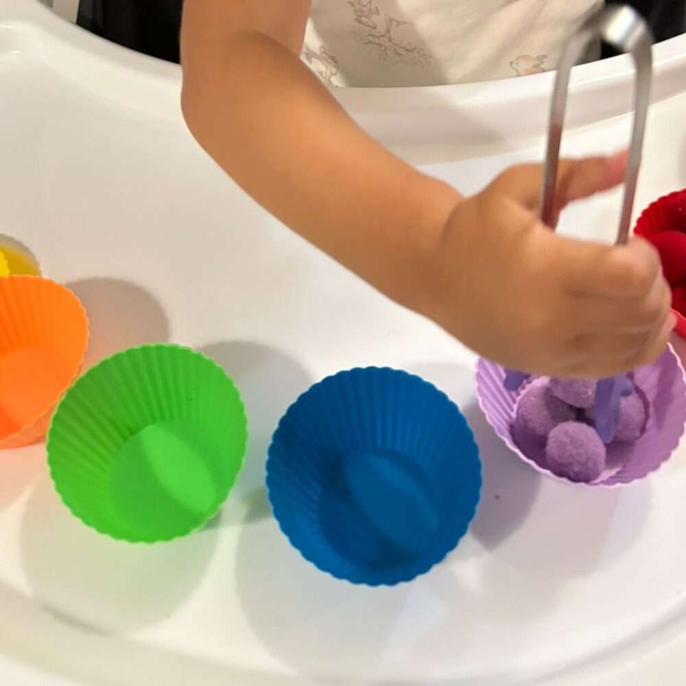 Sorting pom-poms into rainbow silicone cups